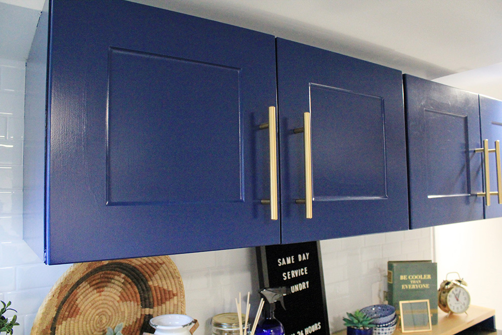 A pair of blue upper cabinets with gold hardware.