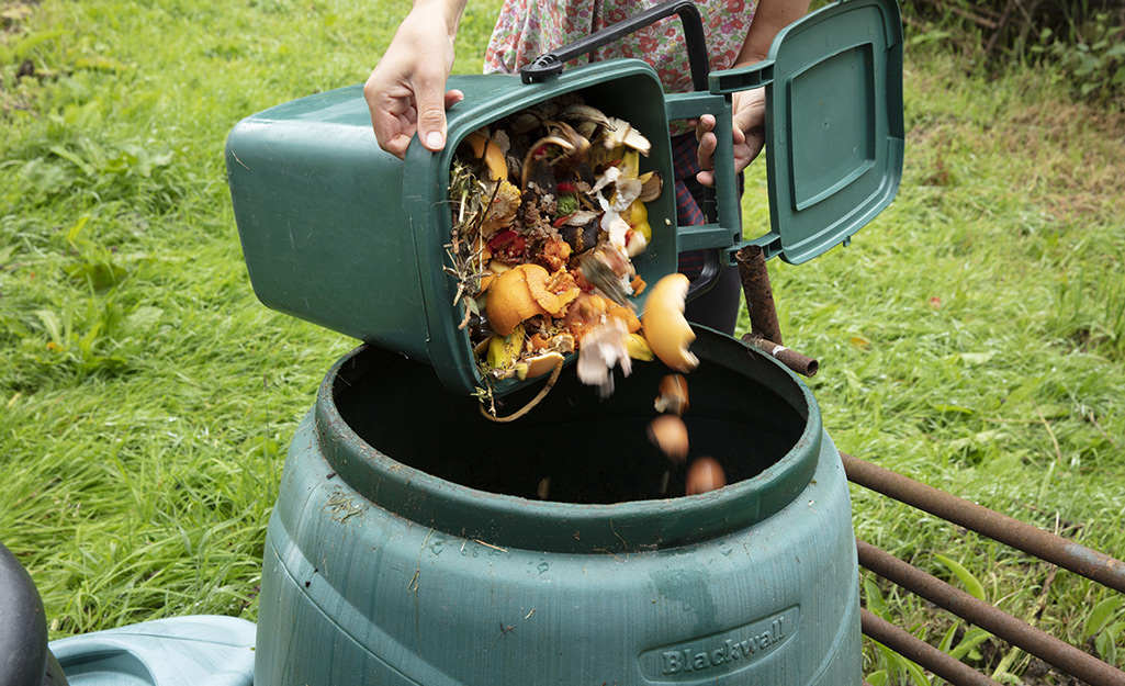 Someone pouring compost into a composter.