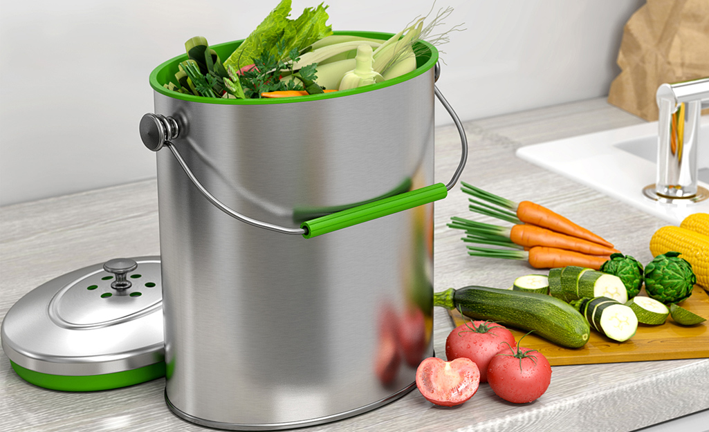 A compost pail in a kitchen and filled with veggie scraps.