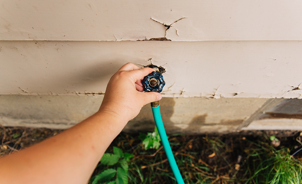 A person turning off a water spigot.