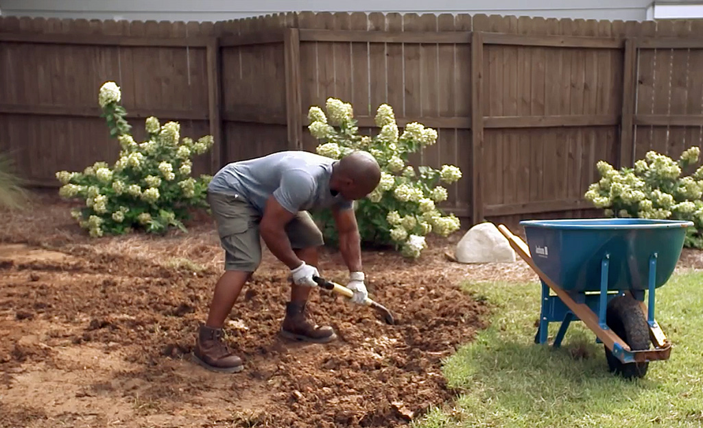 A person digging out an area for a swing set.