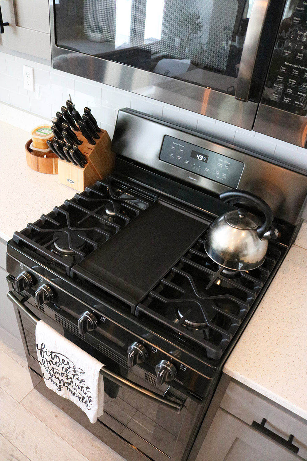 A GE black stainless steel gas range with a griddle. 