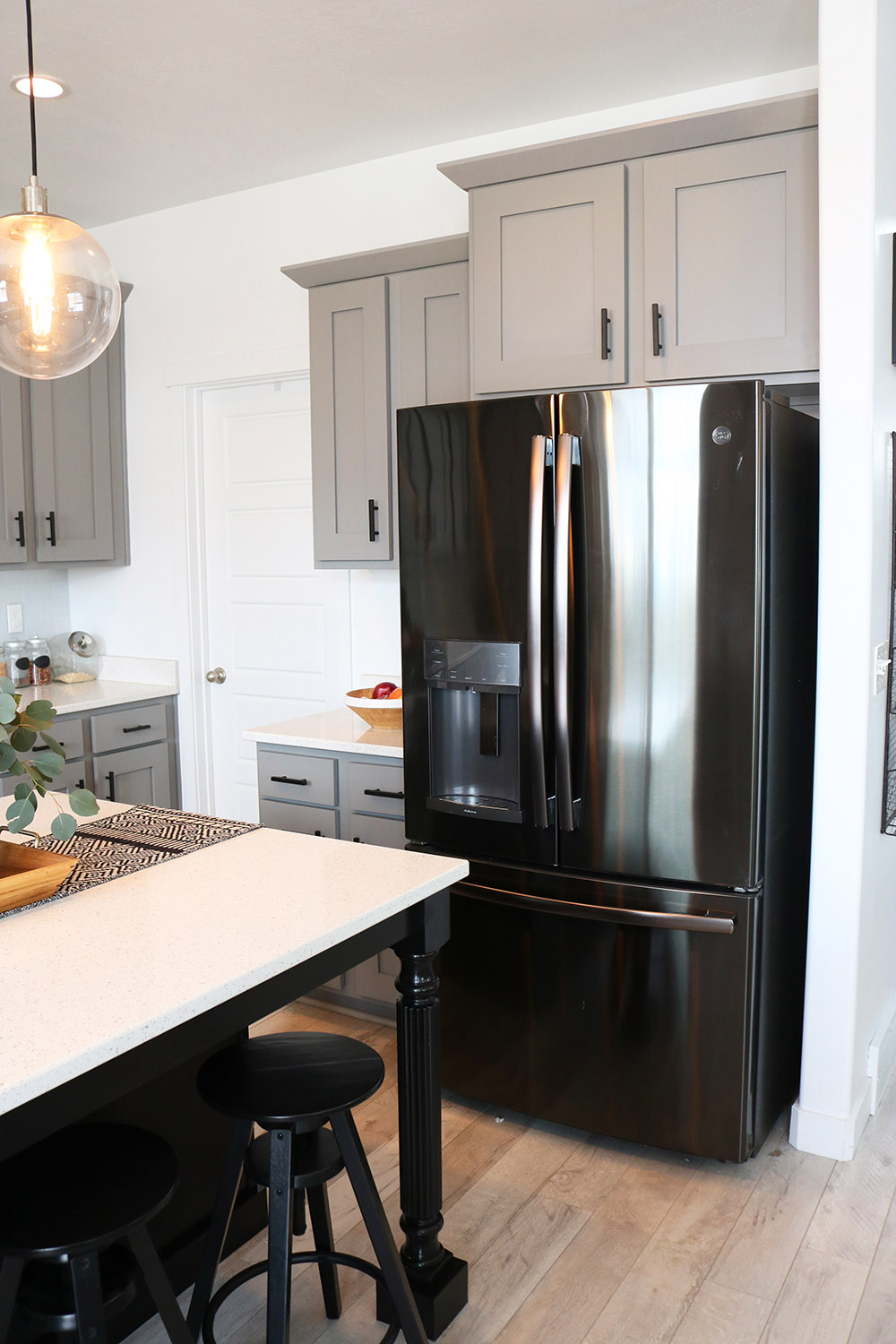 A GE black stainless steel refrigerator in a kitchen.