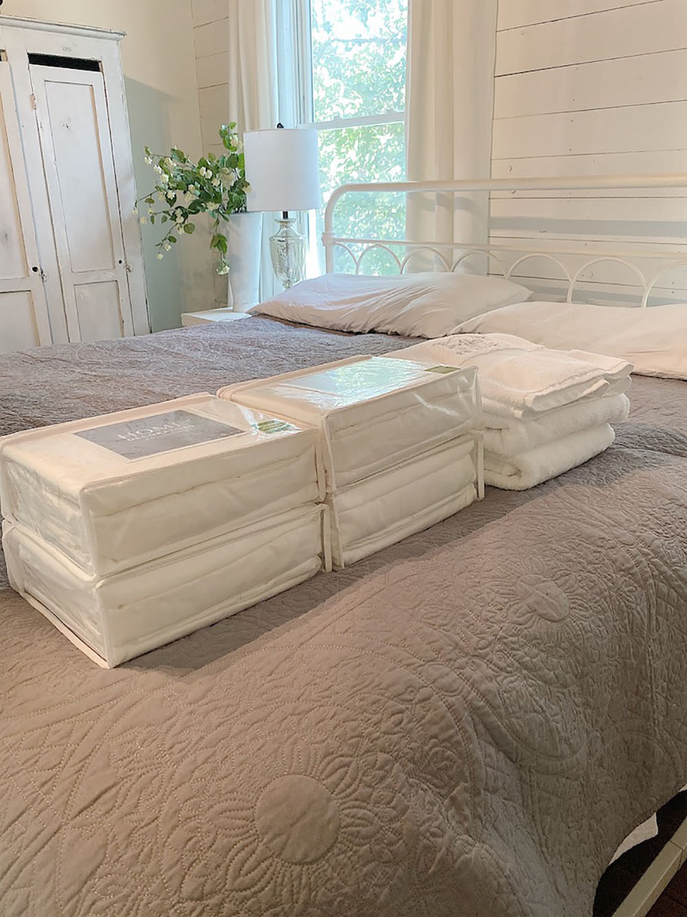 A group of sheet sets and towels sitting on top of gray bedding.