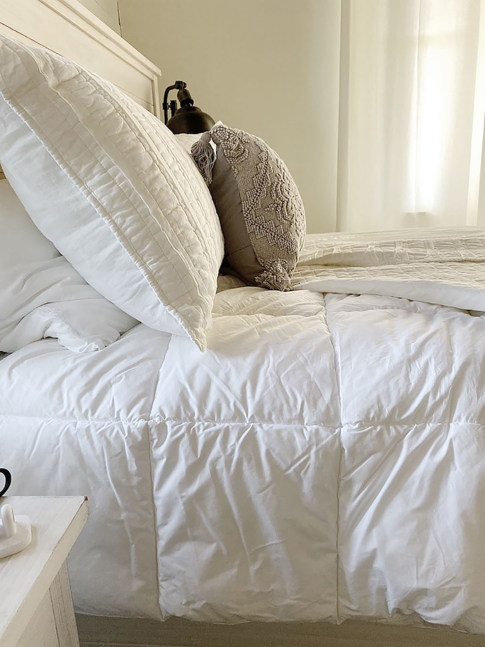 A bed made with a white down alternative cotton comforter.