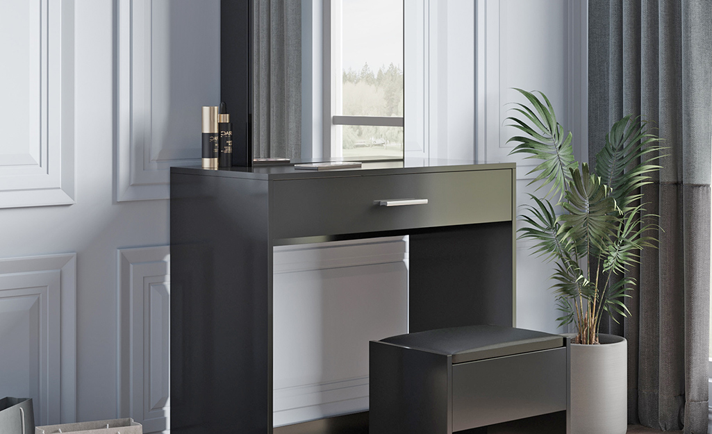 A black vanity with minimalist style sits next to a potted plant.