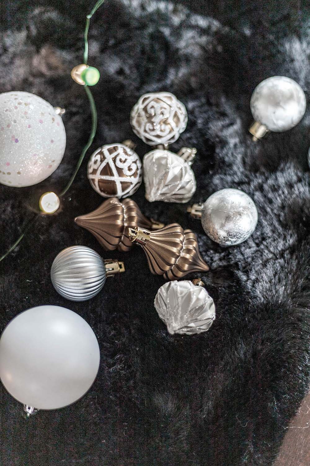 A group of silver and bronze ornaments sitting on a fuzzy blanket.