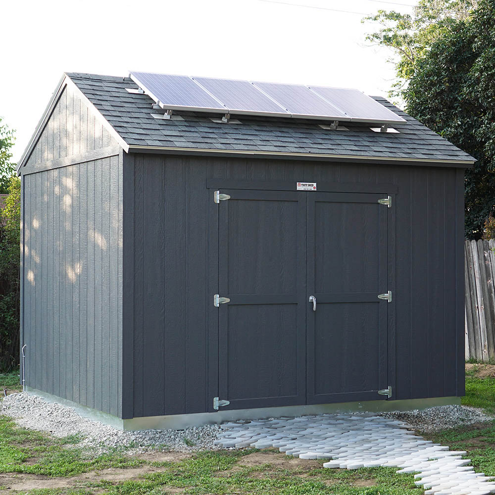 The exterior of a dark colored Tuff Shed with solar panels on the roof.