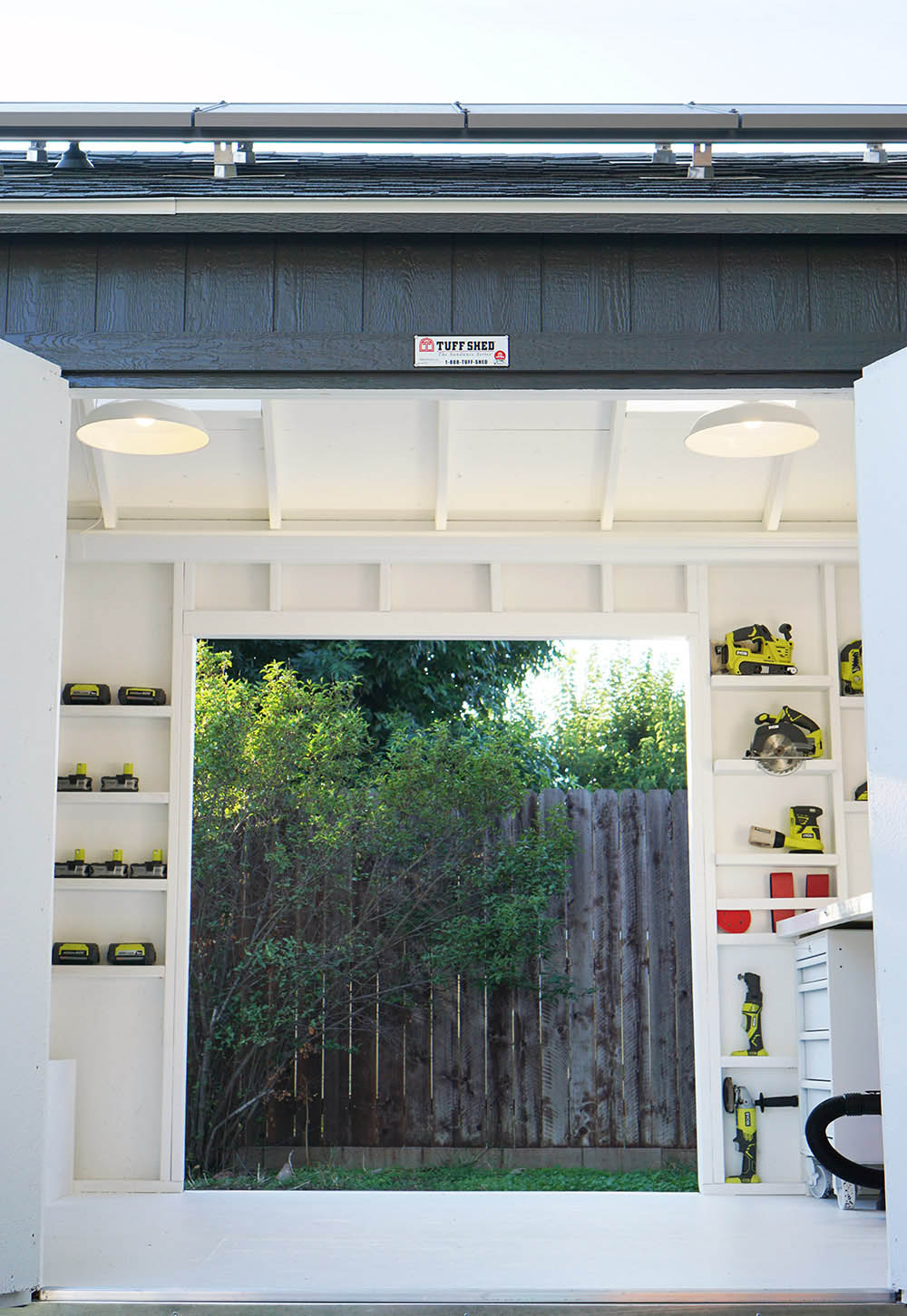 A pair of white pendant lights hanging from the ceiling of a Tuff Shed.