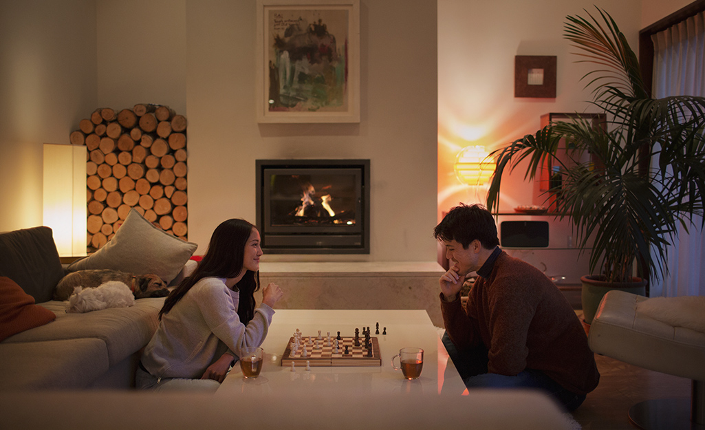 Two people playing a board game in a living room with warm white lighting.