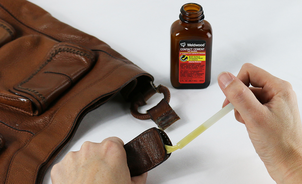 A person uses contact cement to repair a vinyl strap.