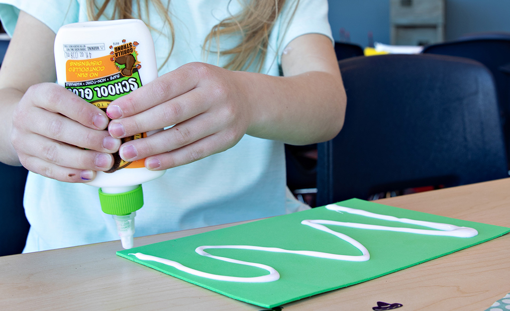 A child using craft glue on construction paper.