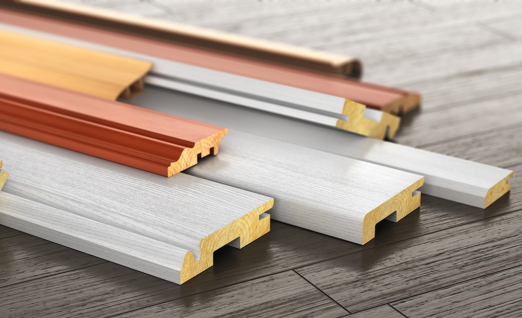 A stack of baseboard moulding samples on a wood floor.