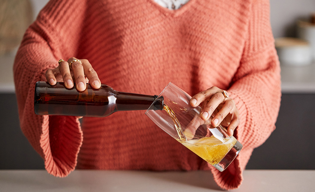 A person pours beer into a pilsner glass