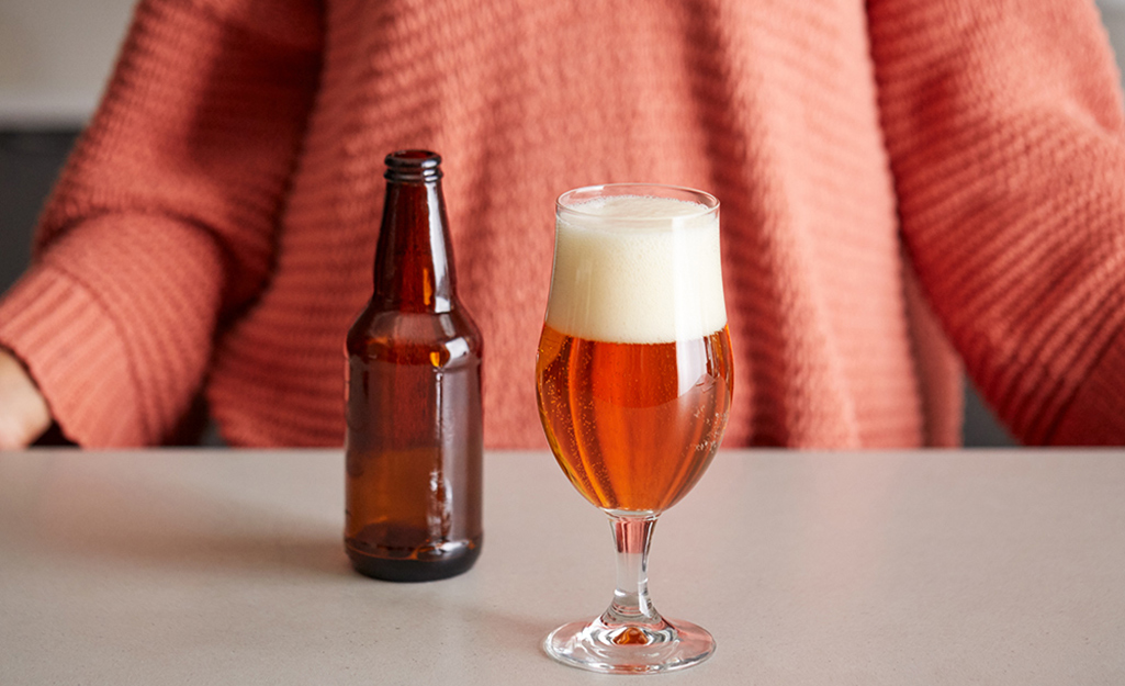 A filled tulip style beer glass on a counter.