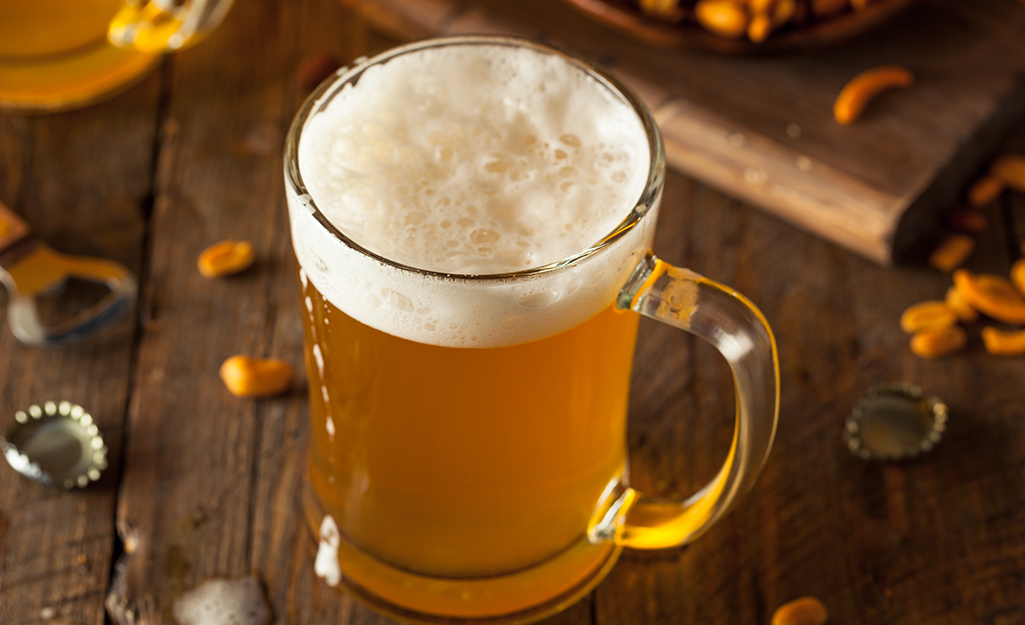 A glass mug of beer on a table.