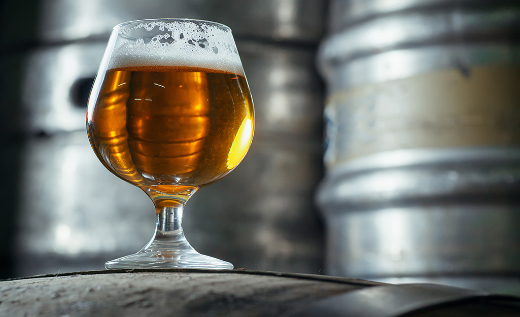 A goblet of beer in front of metal beer casks.