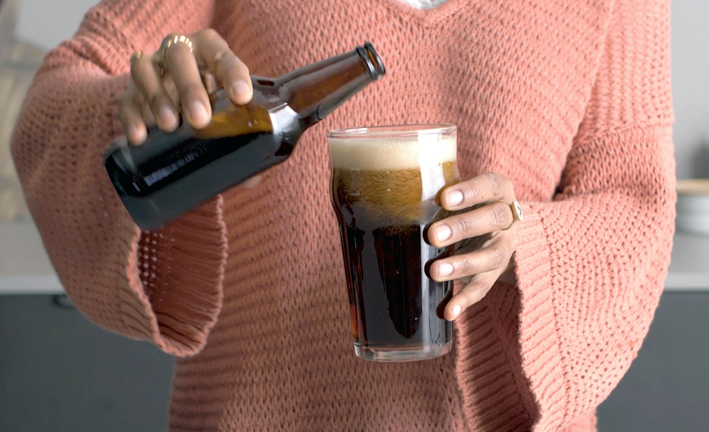 A person holds a pint of beer poured from a bottle.