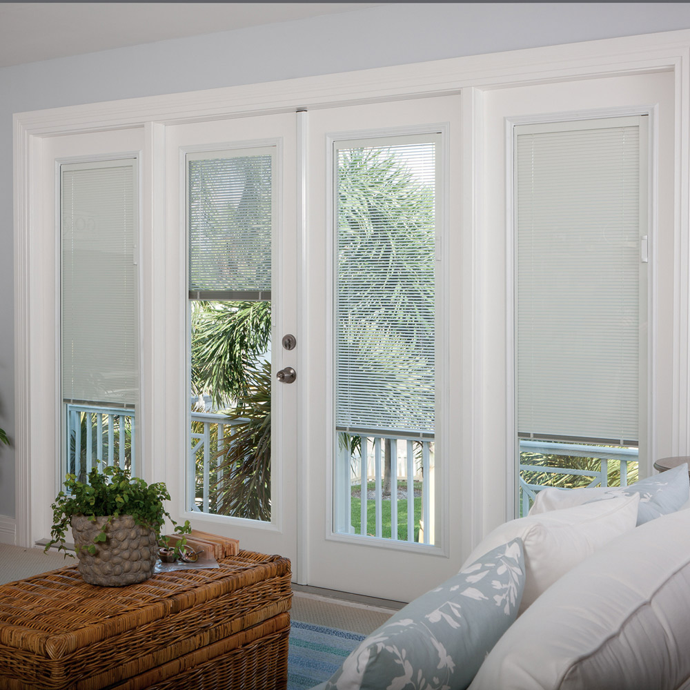 Blinds cover the floor-to-ceiling windows and glass door of a light-filled living room. Blinds cover the floor-to-ceiling windows and glass door of a light-filled living room.