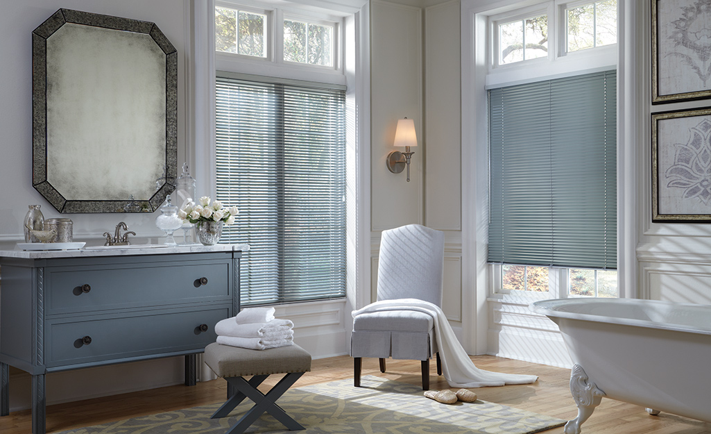 Blue-gray blinds match the color scheme of a large bathroom with a claw-foot tub.