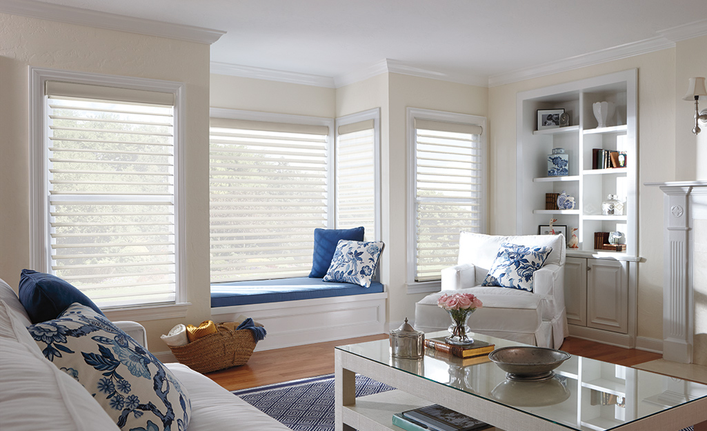 Continuous cord blinds hang in the windows of a comfortable living room with a window seat.