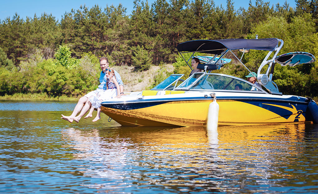 A man and a girl sit on the bow of a yellow boat, while three people are inside the boat.