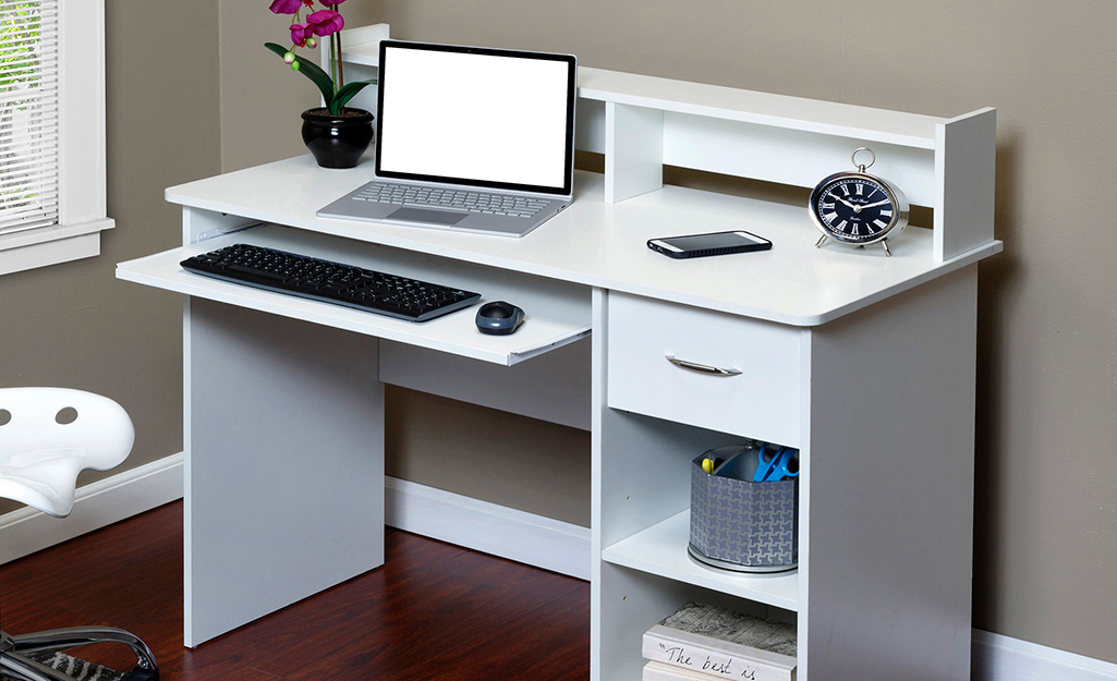 A small home office desk has a sliding keyboard tray.