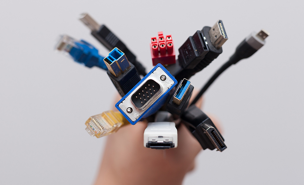 A person holds cables with varied types of connectors.