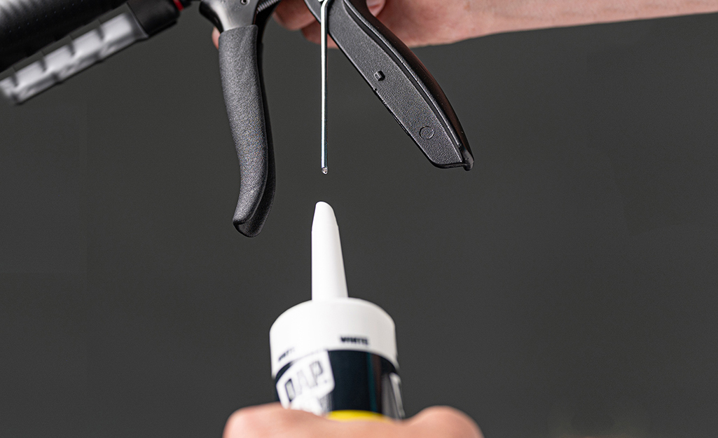 A person preparing a caulk cartridge for use