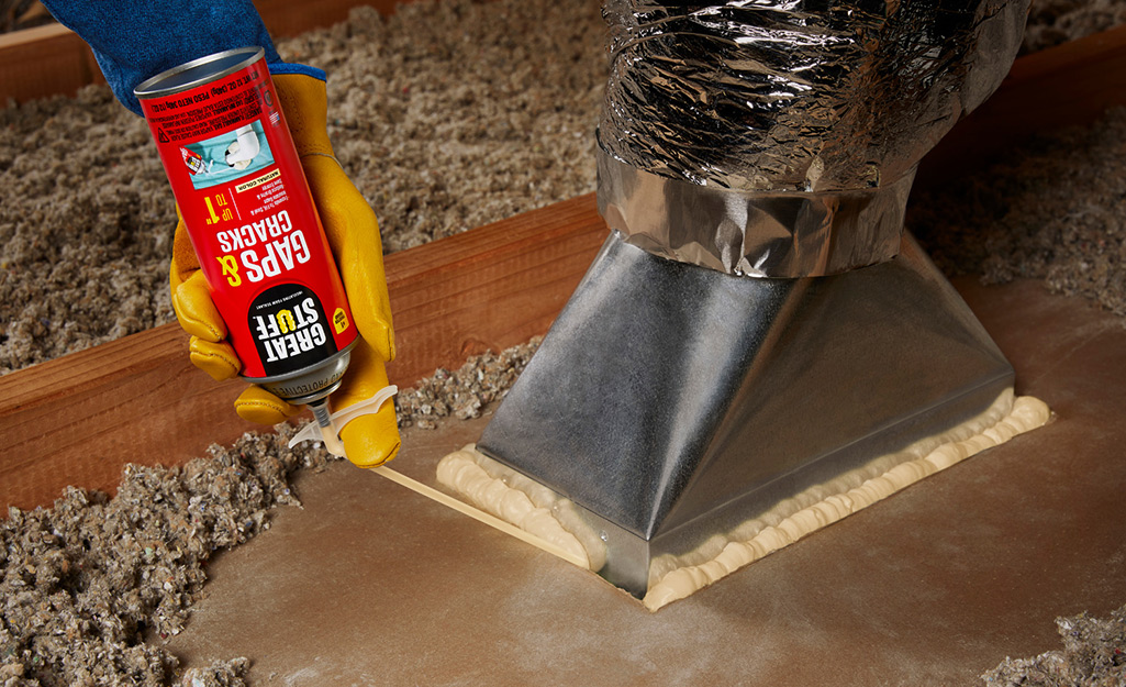 Person spraying expandable foam to seal ductwork