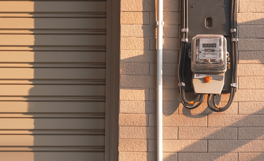 Conduit runs from an electric meter box on a brick exterior wall.