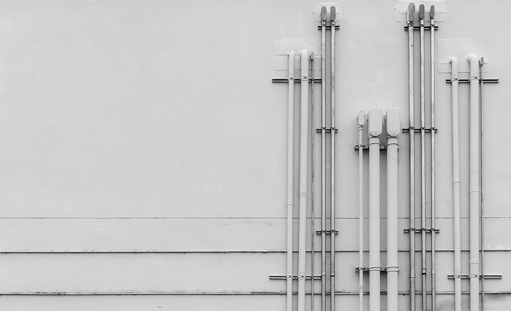 Various sizes of conduit strapped to a wall.