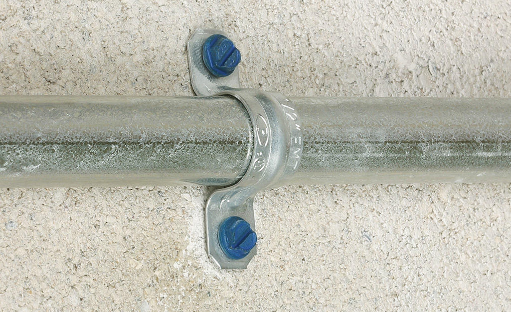 A conduit strap holding a conduit in place. 