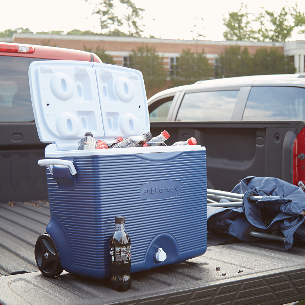 A cooler filled with ice and drinks sits on the tailgate of a pickup truck.