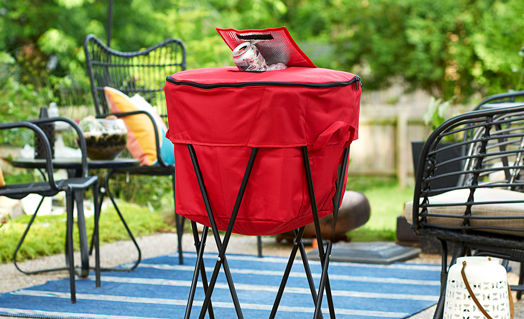 A soft-sided cooler with a folding stand sits on a patio.