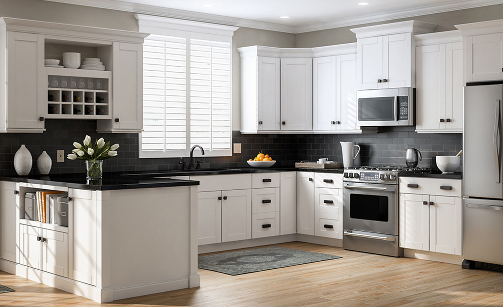 A kitchen with white cabinets and black countertops.