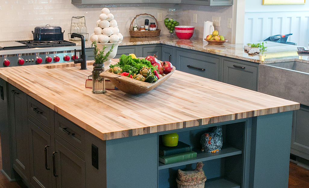 A kitchen with butcher block countertops paired with green cabinetry.