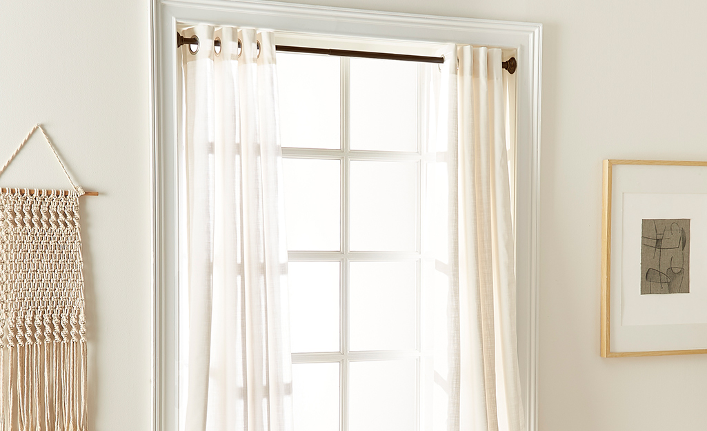 A tension rod holding curtains up in a corner window.
