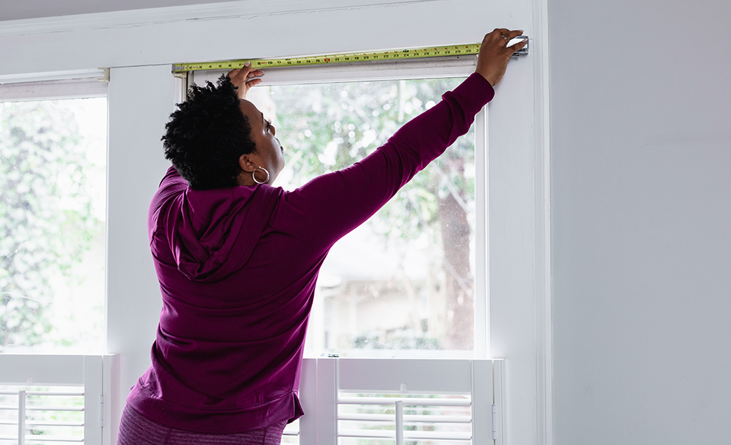 A woman measuring a window frame.