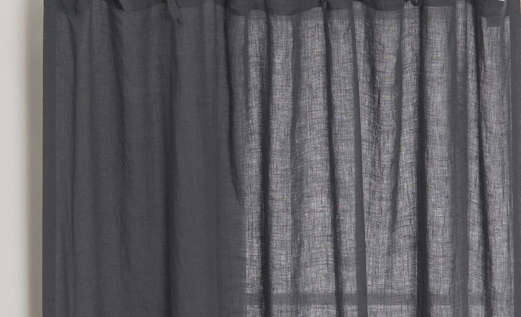A dark curtain with some light filtering in.