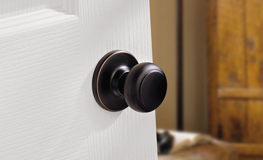 A dark brown passage door knob on a white door.