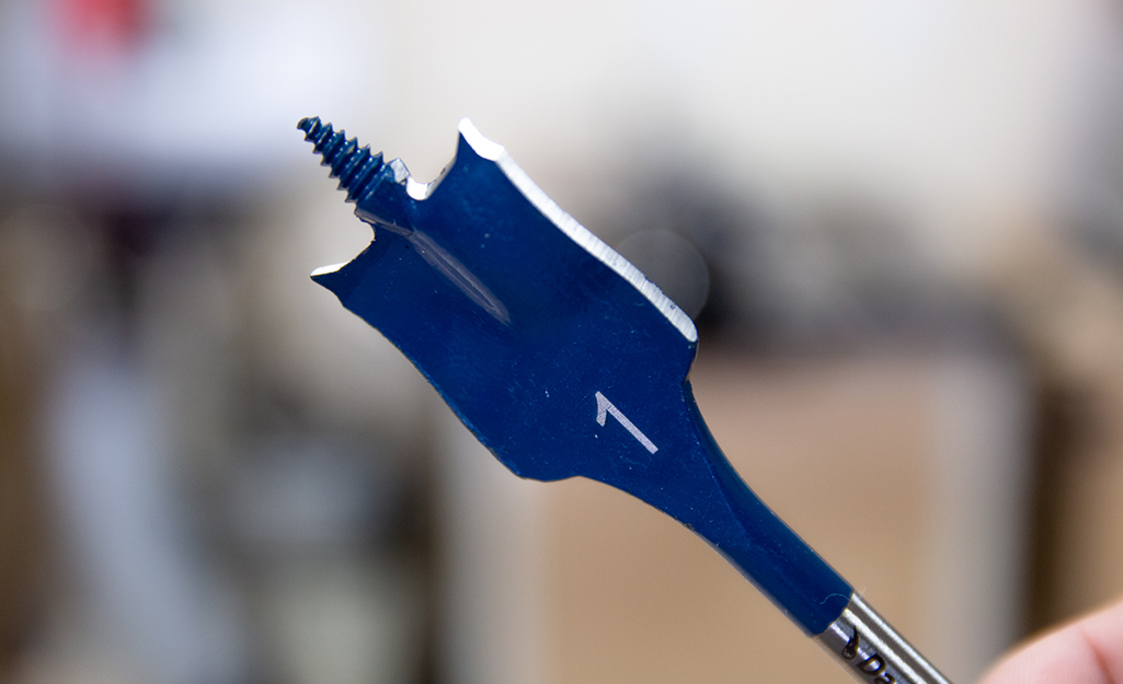 Someone holding a spade drill bit. Someone holding a spade drill bit.