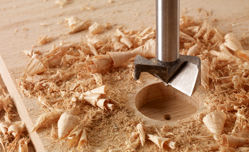 A Forstner drill bit being using to make a hole in a board. A Forstner drill bit being using to make a hole in a board.