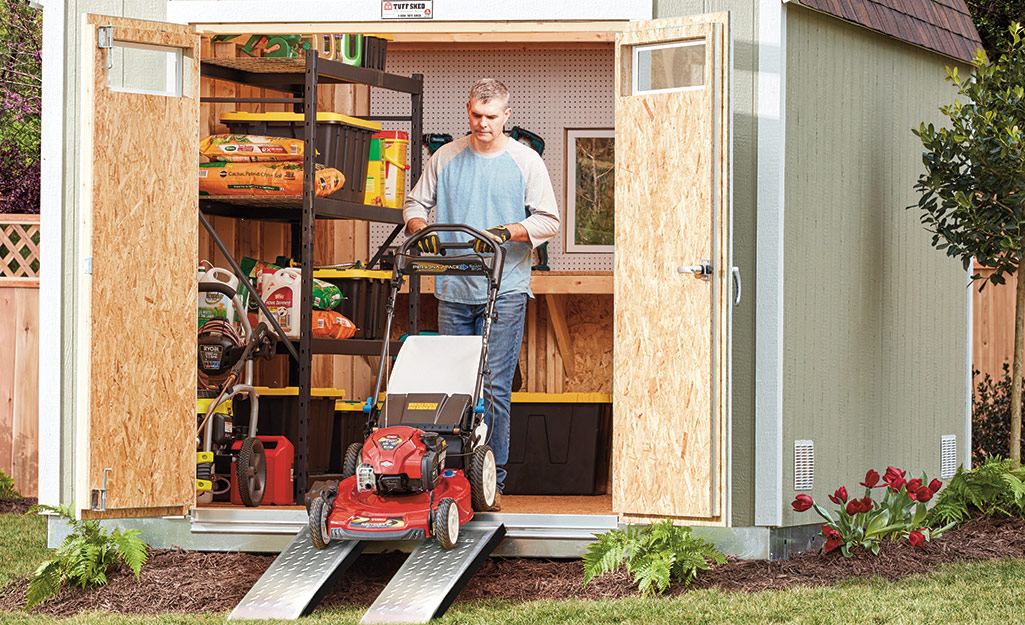 Someone moving their mower into a storage shed. Someone moving their mower into a storage shed.