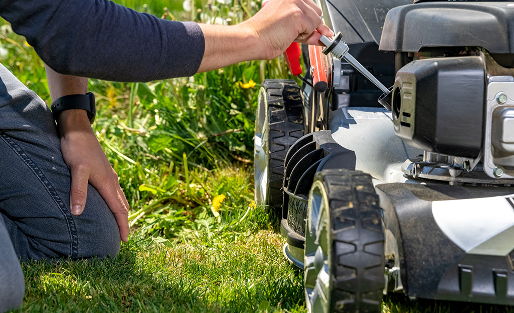 Someone adding oil to their lawn mower. Someone adding oil to their lawn mower.
