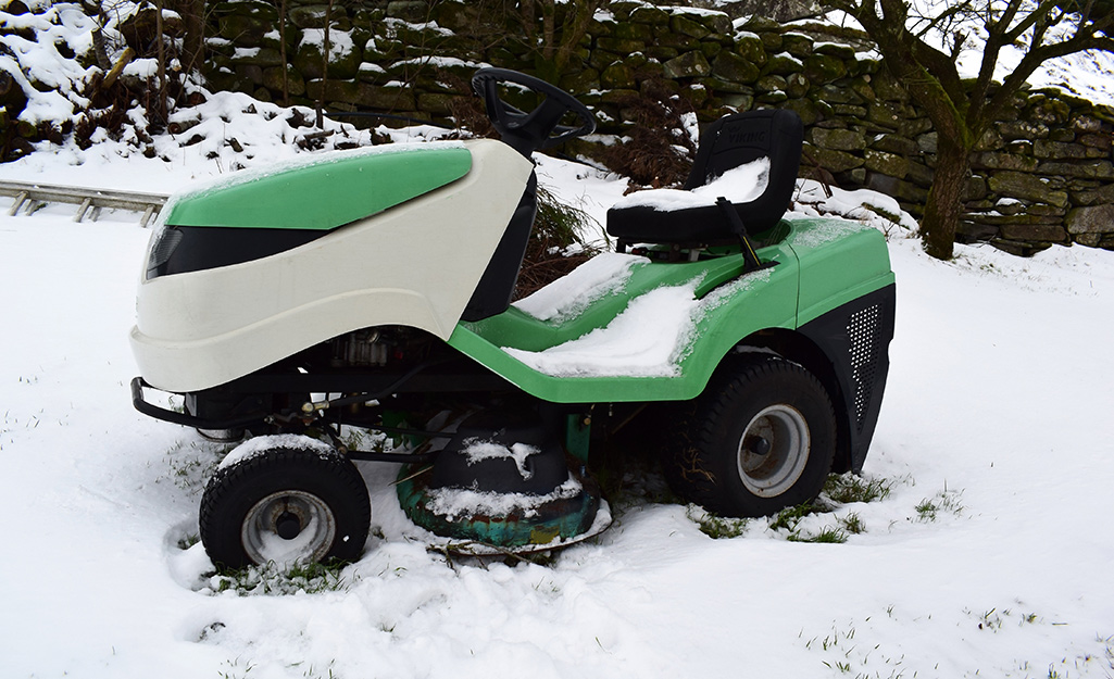 A riding lawn mower in snow. A riding lawn mower in snow.