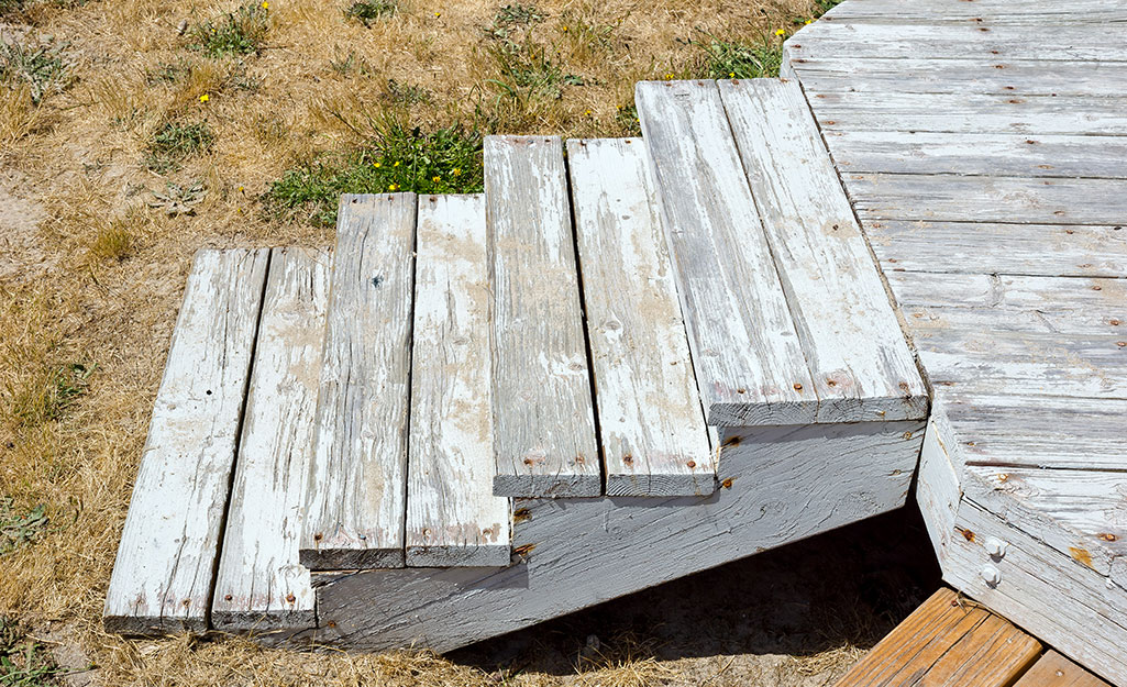 Unsealed wood deck steps that are weather- and water-damaged.