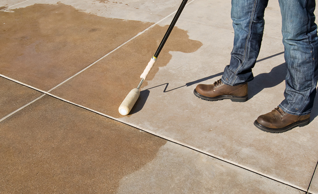 A person using a roller brush to waterproof concrete.