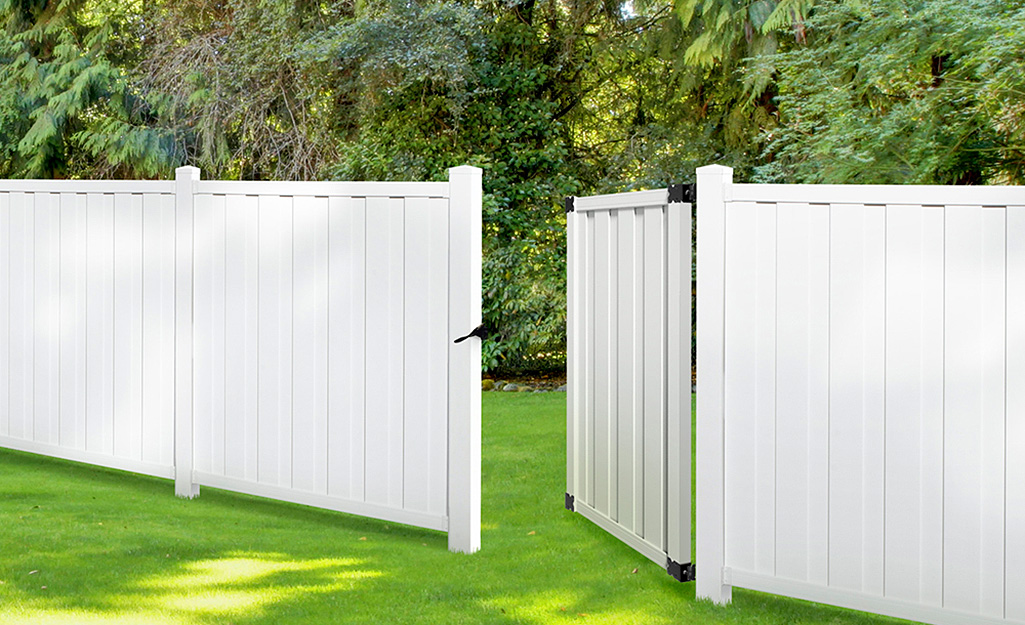 A white vinyl fence with an open gate.