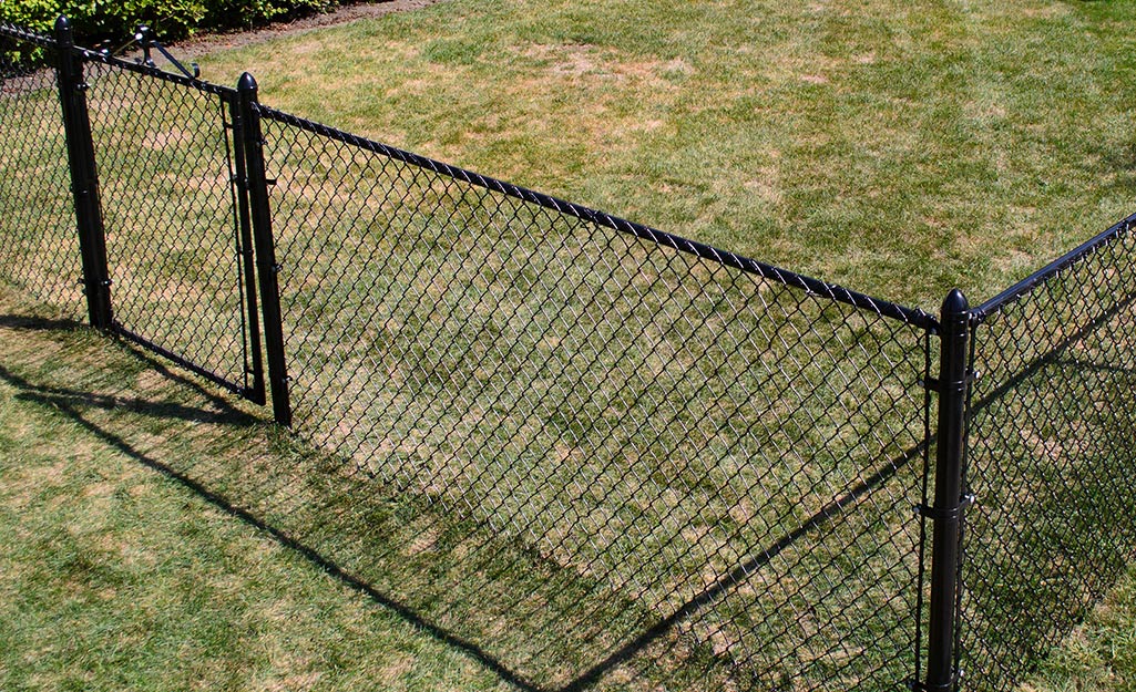 A black chainlink fence installed in a grassy yard.